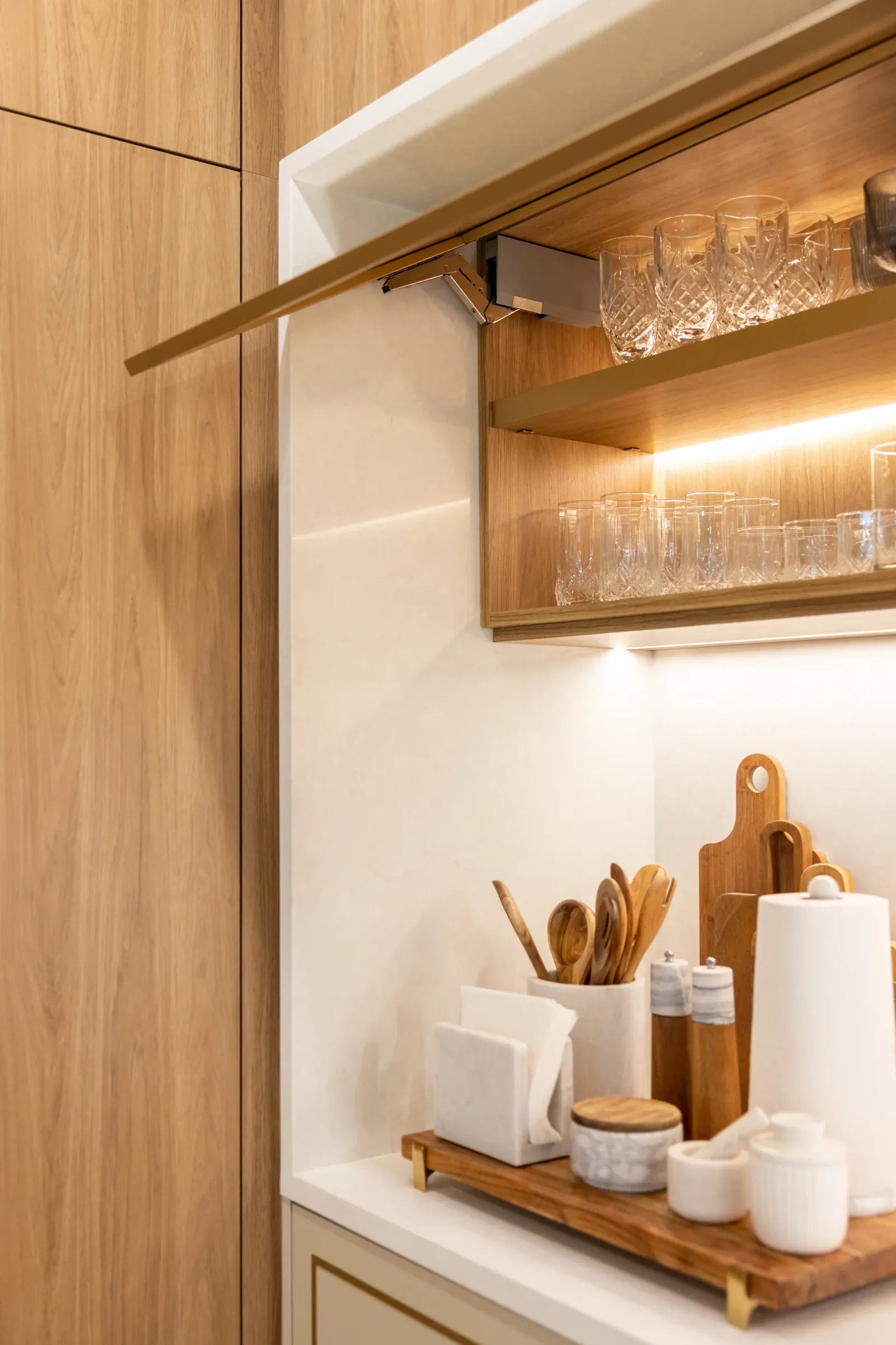 Lift-up cabinet door revealing lit glassware shelves