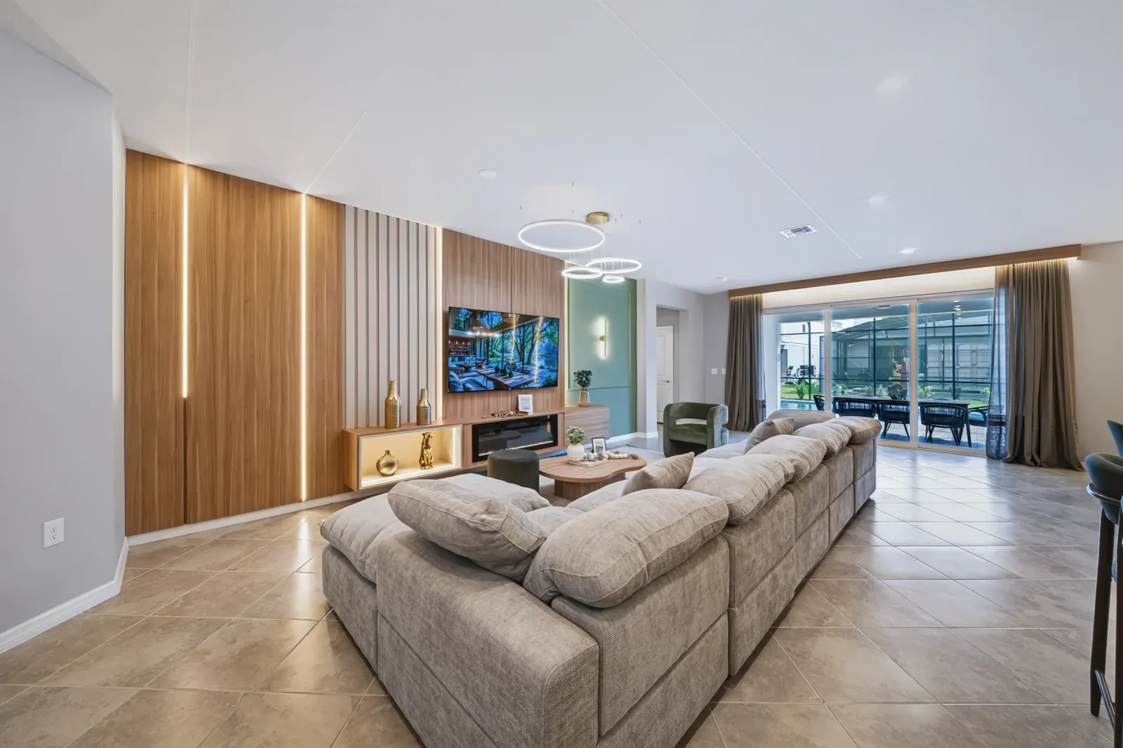 Open living room with wood feature wall and sliding doors to the pool